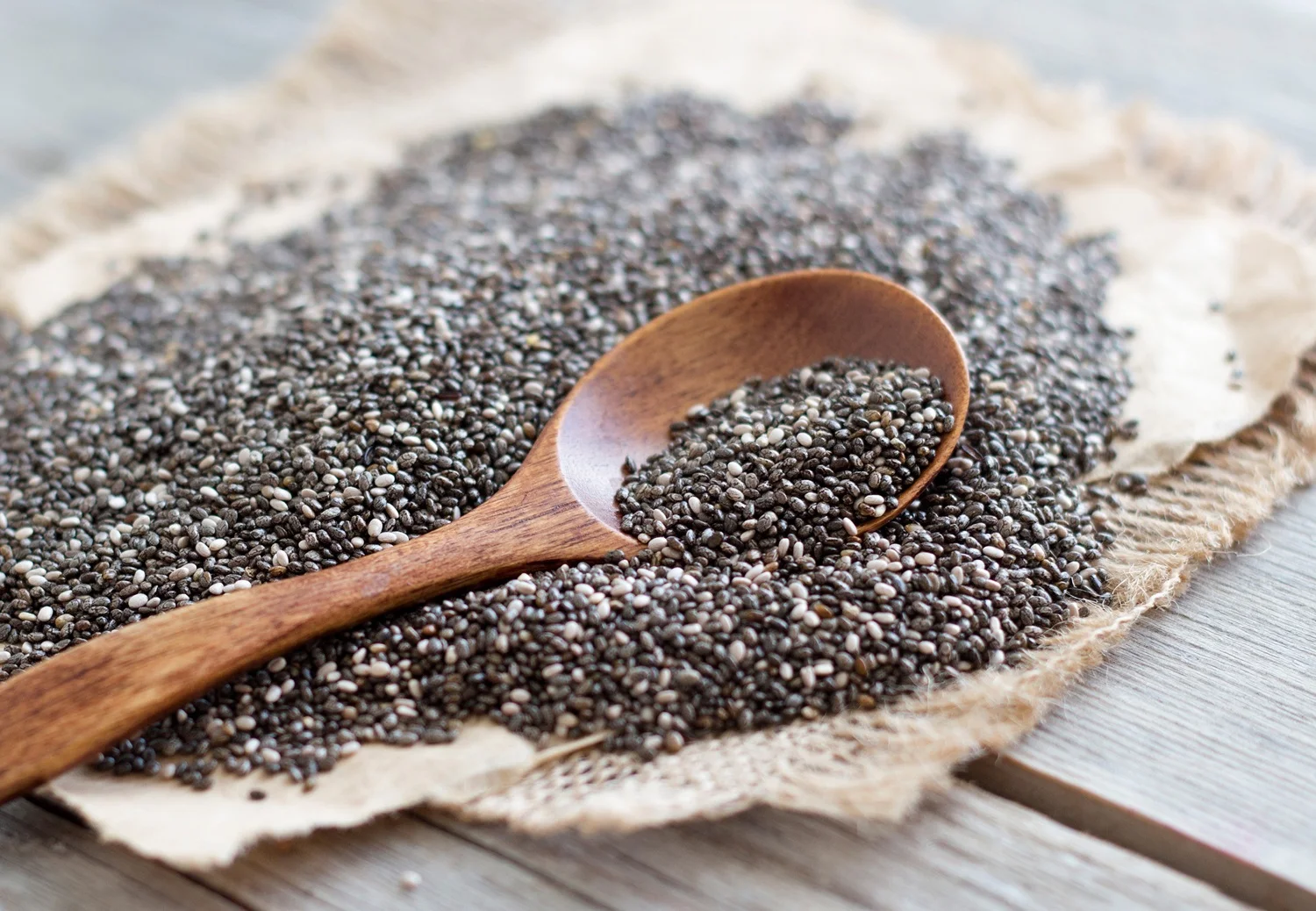 Wooden spoon with raw chia seeds showing chia seeds calories per serving.